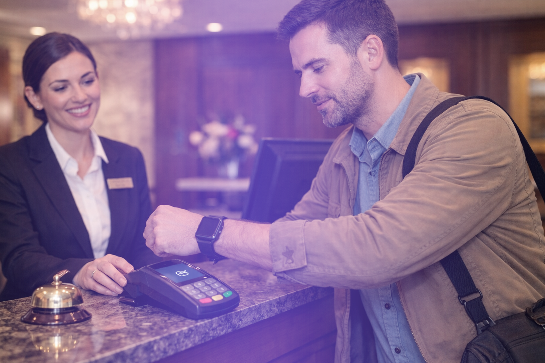 A hotel guest paying at a terminal using contactless payment technology.