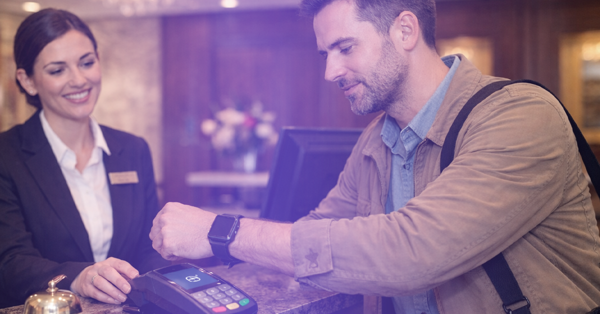 A hotel guest paying at a terminal using contactless payment technology.